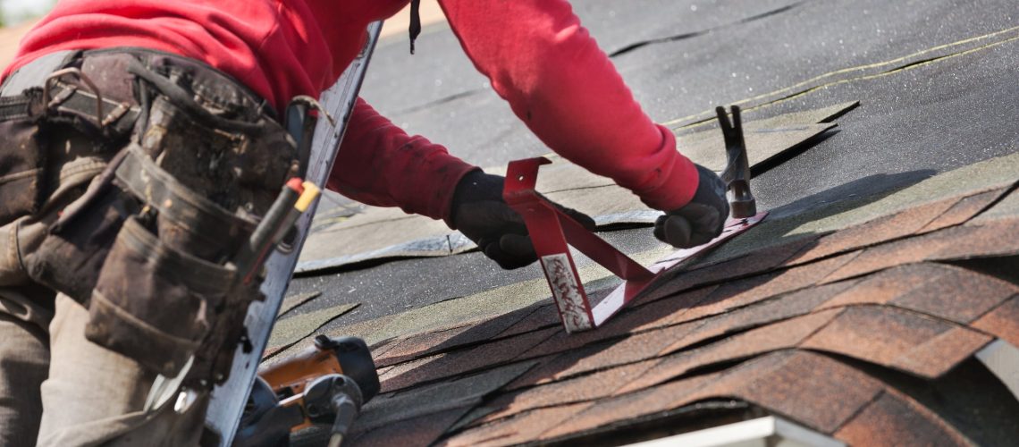 roofers installing a new roof on residential home. weatherlock material and brown asphalt roofing shingles