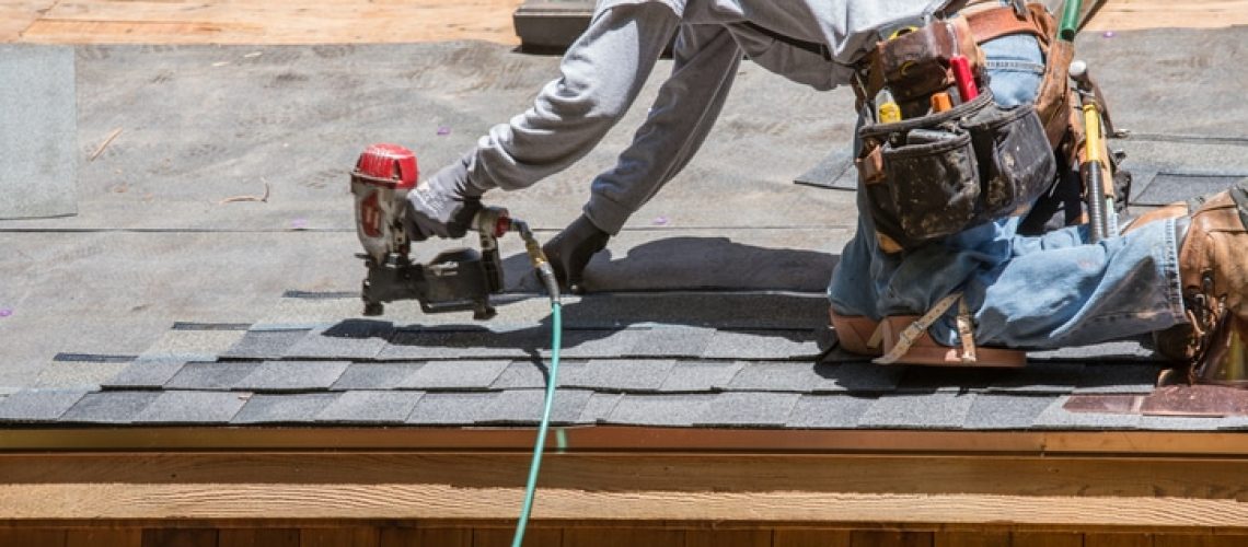 Installing new roof with  nail gun and shingles